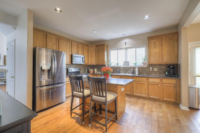 kitchen featuring appliances with stainless steel finishes, a kitchen breakfast bar, sink, light hardwood / wood-style flooring, and a center island