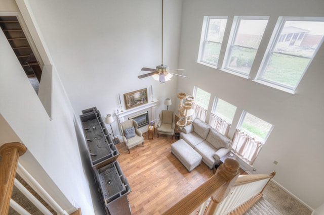 living room featuring ceiling fan, light hardwood / wood-style flooring, and a high ceiling