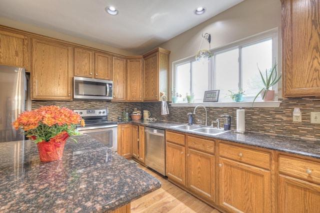 kitchen featuring tasteful backsplash, sink, light hardwood / wood-style floors, and appliances with stainless steel finishes