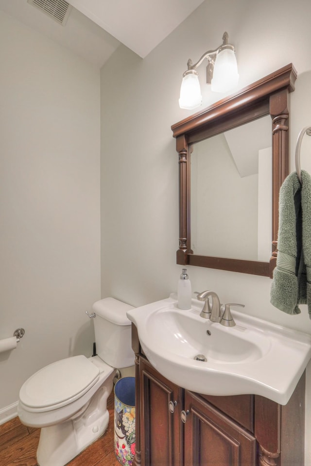 bathroom with toilet, vanity, and hardwood / wood-style flooring