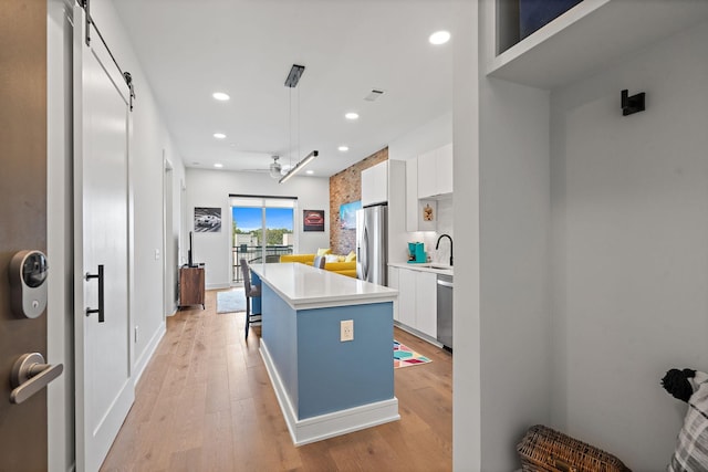 kitchen featuring white cabinets, a center island, a barn door, and appliances with stainless steel finishes