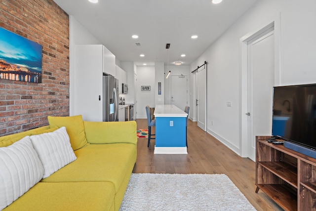 living room with a barn door and light hardwood / wood-style floors