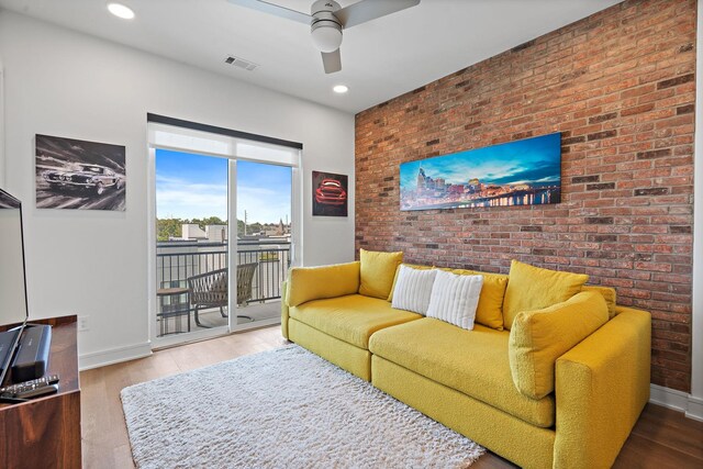 living room with wood-type flooring, ceiling fan, and brick wall