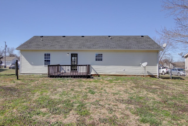 rear view of house with a lawn, a deck, and fence