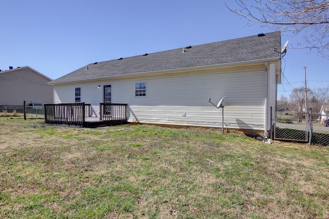 back of house featuring a yard, a shingled roof, a wooden deck, and fence