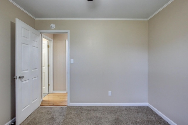 carpeted spare room with baseboards and crown molding