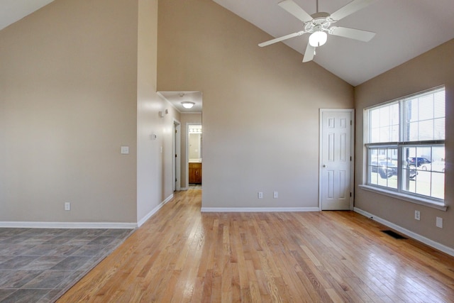 spare room with high vaulted ceiling, light wood-style floors, baseboards, and ceiling fan