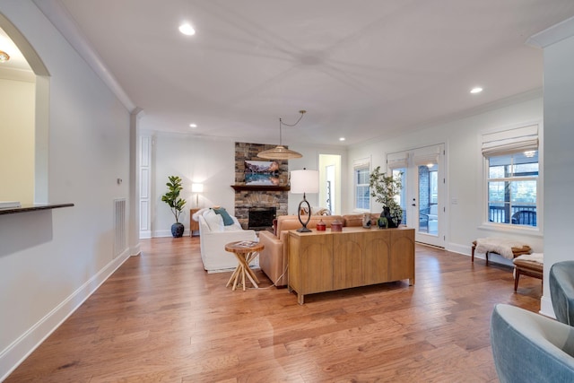 living room with light wood-style flooring, a fireplace, crown molding, and recessed lighting