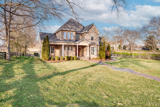 view of front of house with a front lawn, fence, and brick siding