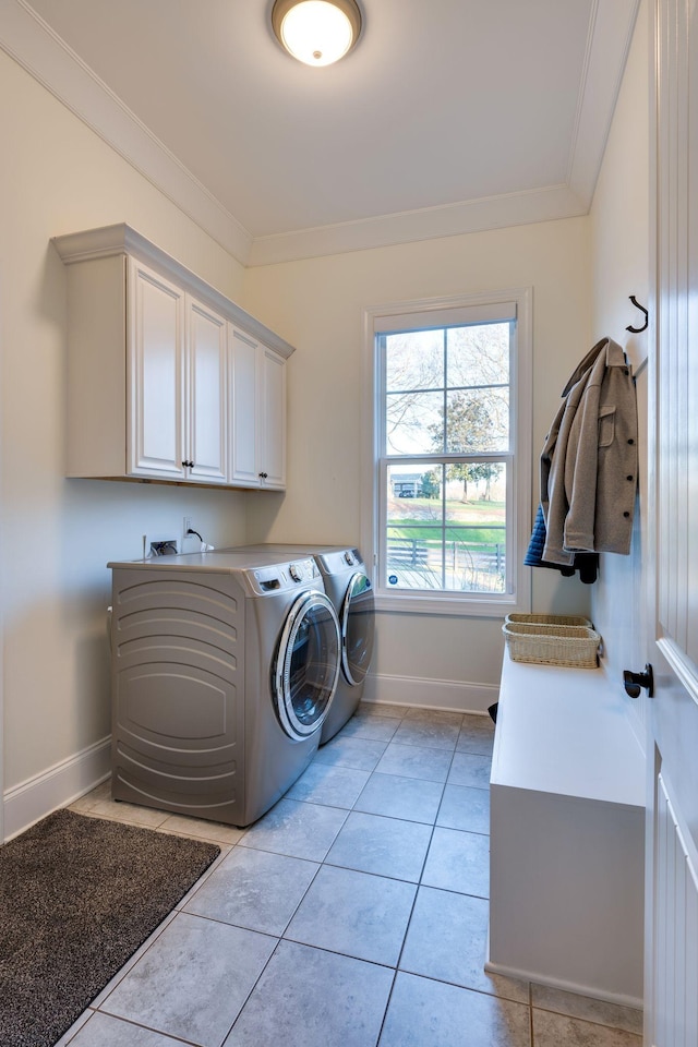 laundry area featuring light tile patterned floors, baseboards, independent washer and dryer, cabinet space, and crown molding