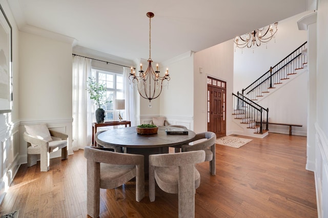 dining room featuring crown molding, a notable chandelier, stairway, and wood finished floors