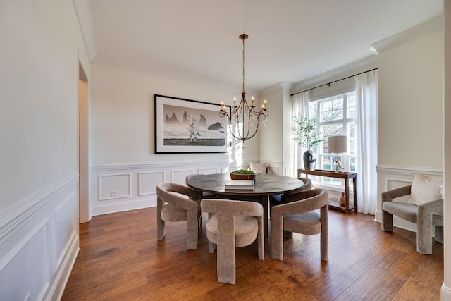 dining area featuring crown molding, a decorative wall, dark wood-style flooring, and a notable chandelier