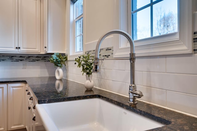 details featuring tasteful backsplash, a sink, and white cabinetry