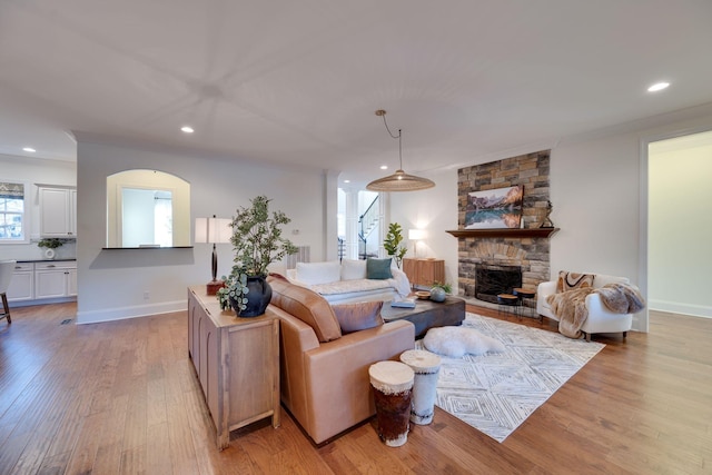 living room with light wood finished floors, a fireplace, baseboards, and recessed lighting