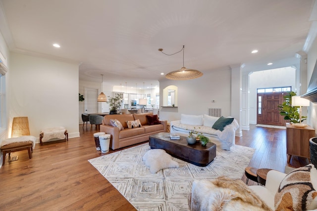 living room with recessed lighting, wood finished floors, visible vents, baseboards, and crown molding