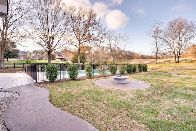 view of yard with a rural view, a patio area, fence, and a pool