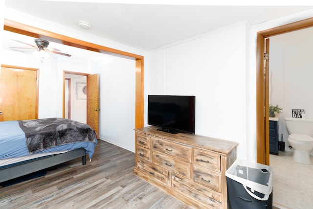 bedroom featuring wood-type flooring, ensuite bathroom, ceiling fan, and ornamental molding