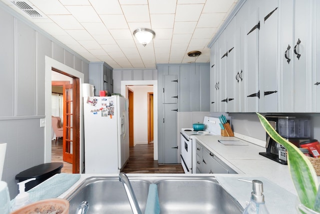 kitchen with gray cabinetry, dark hardwood / wood-style flooring, white appliances, and sink