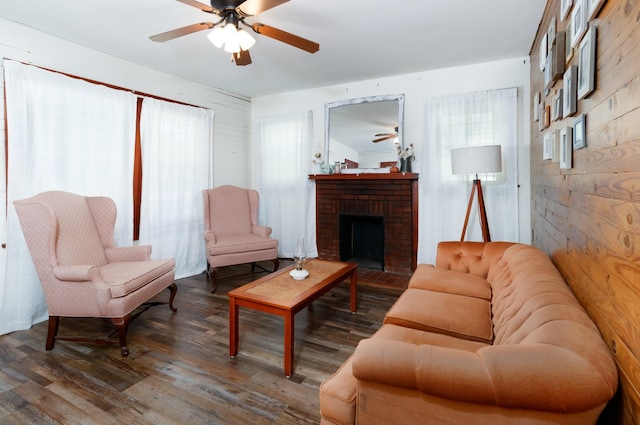 living room with ceiling fan, a fireplace, and dark wood-type flooring