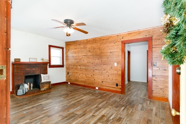 unfurnished living room with a fireplace, wood walls, hardwood / wood-style floors, and ceiling fan