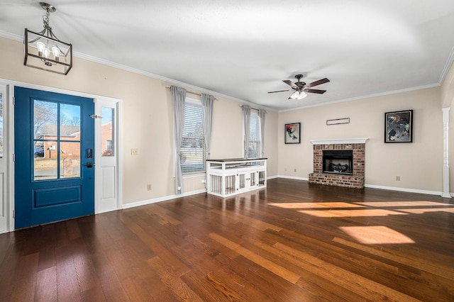 foyer featuring ceiling fan with notable chandelier, dark hardwood / wood-style flooring, ornamental molding, and a brick fireplace