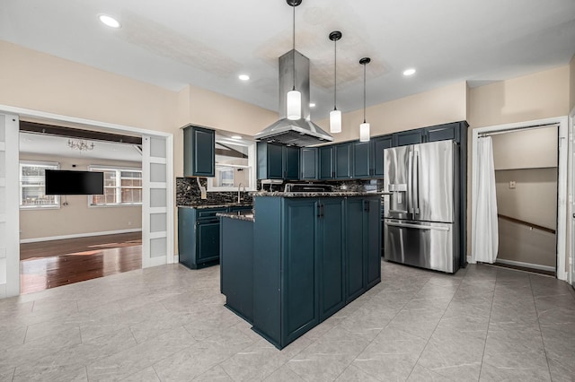 kitchen featuring backsplash, blue cabinets, stainless steel refrigerator with ice dispenser, hanging light fixtures, and island exhaust hood