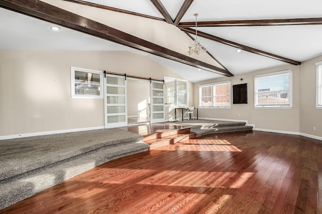 unfurnished living room with wood-type flooring, a barn door, lofted ceiling with beams, and an inviting chandelier