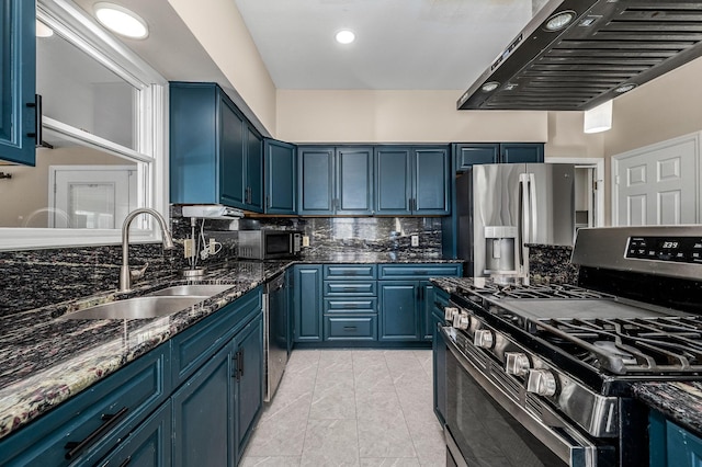 kitchen with blue cabinets, stainless steel appliances, exhaust hood, and dark stone counters