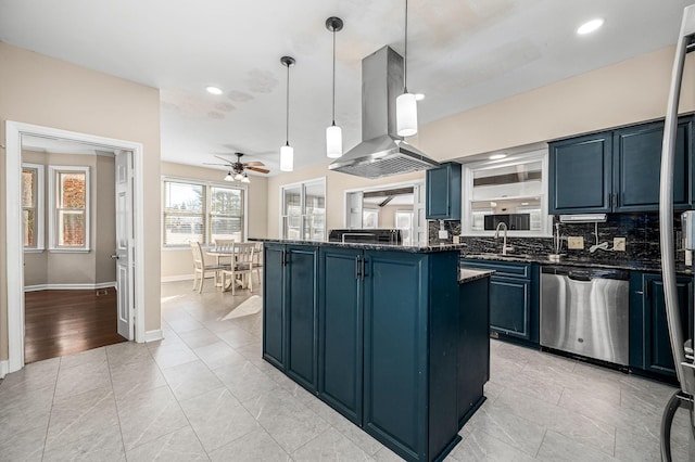 kitchen featuring dark stone counters, hanging light fixtures, stainless steel dishwasher, blue cabinetry, and island range hood