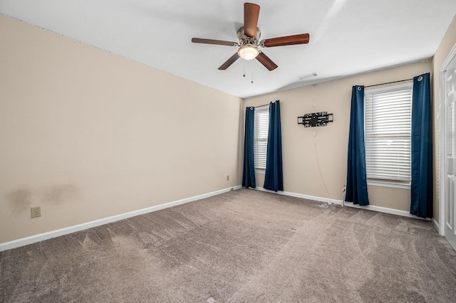 carpeted empty room with ceiling fan and plenty of natural light