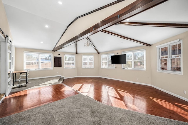 unfurnished living room featuring vaulted ceiling with beams, a barn door, and hardwood / wood-style floors