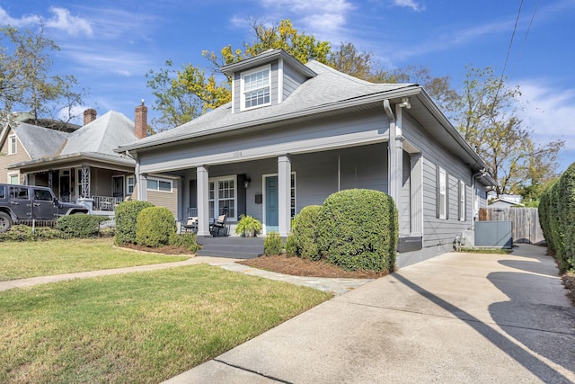 bungalow-style house featuring covered porch and a front yard