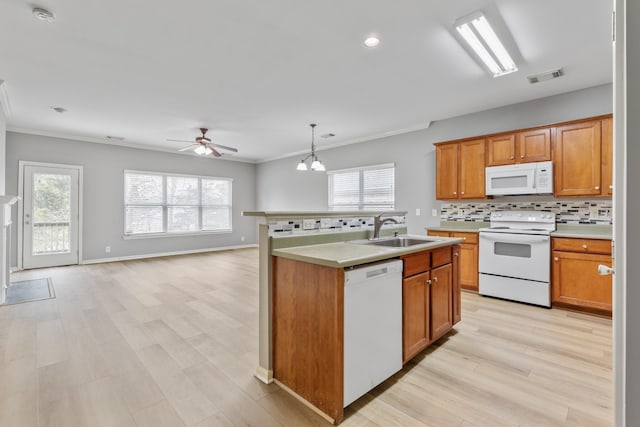 kitchen with sink, an island with sink, pendant lighting, white appliances, and decorative backsplash