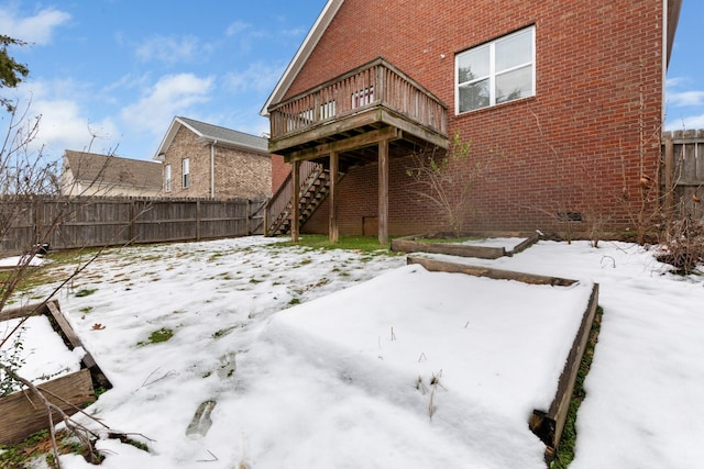 snow covered back of property featuring a wooden deck