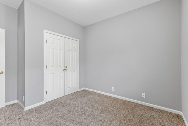 unfurnished bedroom featuring a closet and light colored carpet