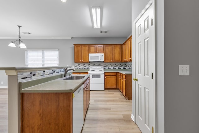 kitchen featuring sink, hanging light fixtures, a notable chandelier, backsplash, and white appliances