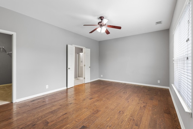 unfurnished bedroom featuring a walk in closet, ceiling fan, multiple windows, hardwood / wood-style floors, and a closet