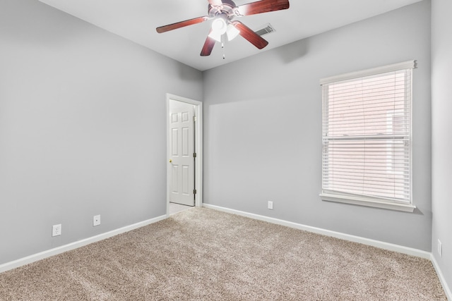 carpeted spare room featuring ceiling fan and plenty of natural light