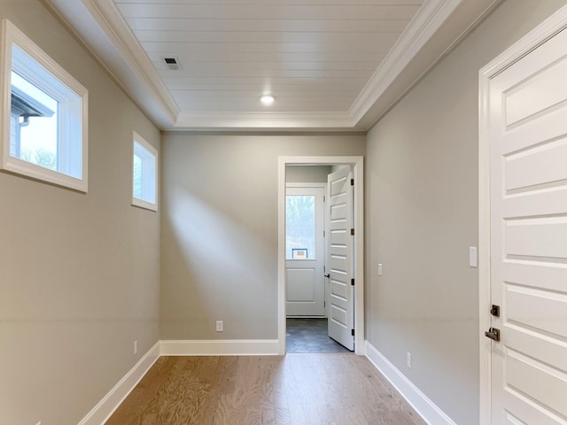 empty room featuring hardwood / wood-style floors, a raised ceiling, plenty of natural light, and crown molding