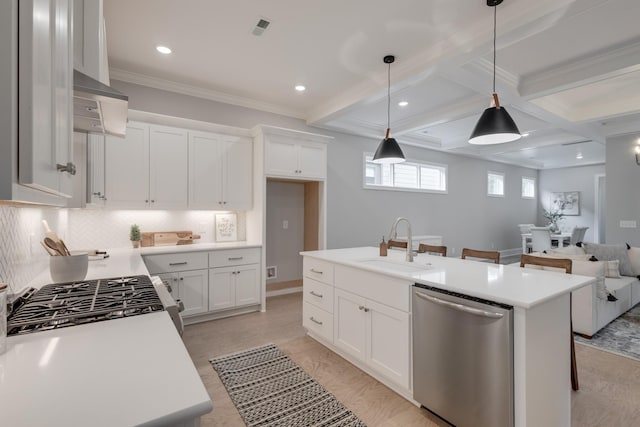 kitchen with appliances with stainless steel finishes, decorative light fixtures, white cabinetry, and a kitchen island with sink