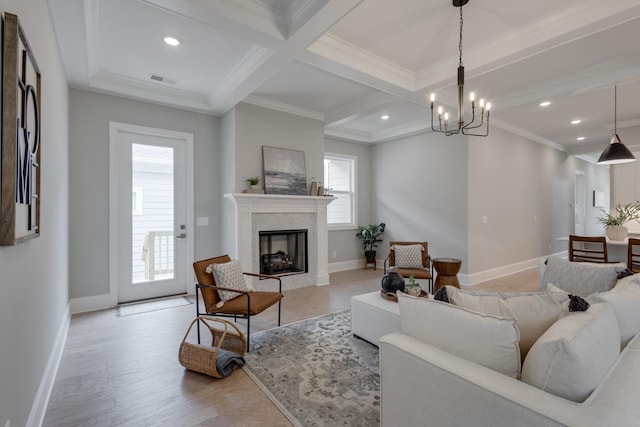 living room featuring beamed ceiling, ornamental molding, plenty of natural light, and coffered ceiling