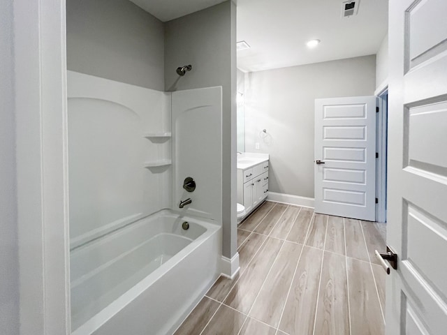 full bathroom featuring washtub / shower combination, hardwood / wood-style floors, vanity, and toilet