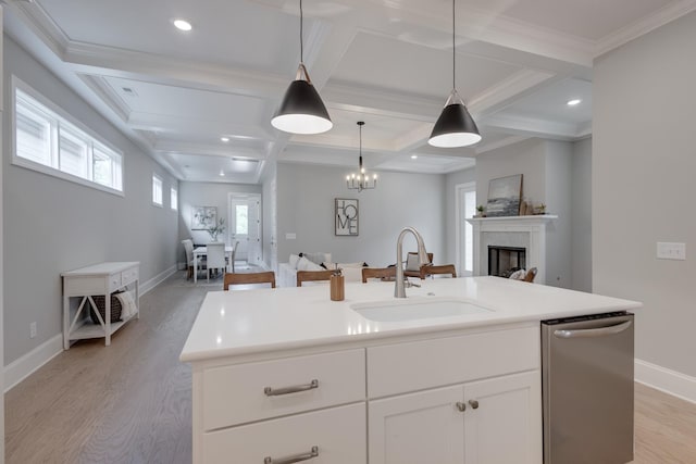 kitchen with coffered ceiling, a kitchen island with sink, sink, white cabinets, and hanging light fixtures