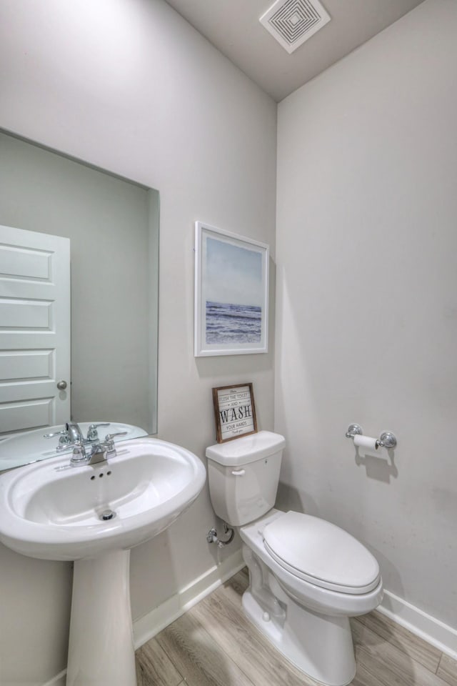 bathroom with toilet, hardwood / wood-style floors, and sink