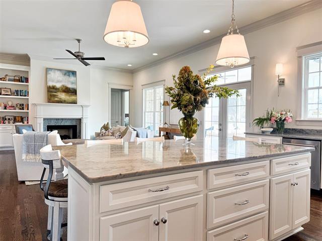 kitchen featuring dishwasher, hanging light fixtures, a center island, light stone counters, and white cabinets