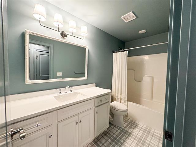 full bathroom with shower / bathtub combination with curtain, vanity, tile patterned floors, and toilet