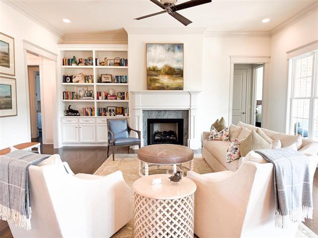 living room with crown molding, ceiling fan, a fireplace, and dark wood-type flooring