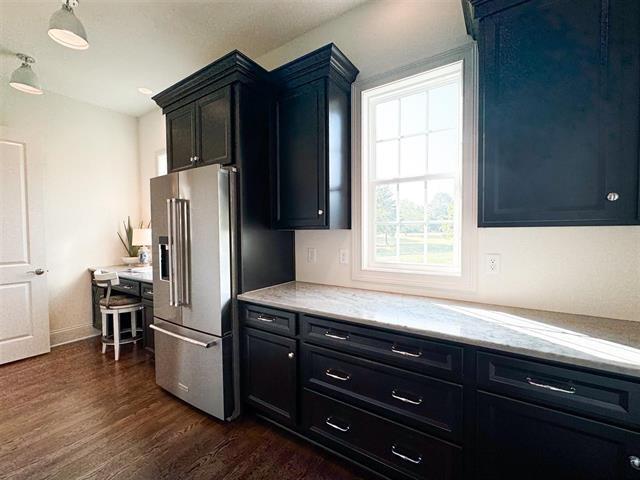 kitchen with light stone countertops, high end fridge, and dark hardwood / wood-style flooring