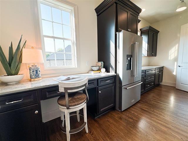 kitchen featuring dark wood-type flooring, high end refrigerator, and light stone counters