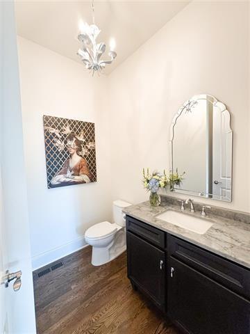 bathroom featuring wood-type flooring, toilet, a chandelier, and vanity